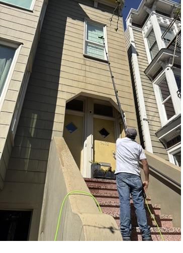Technician washing upper-story siding with a water-fed extension pole