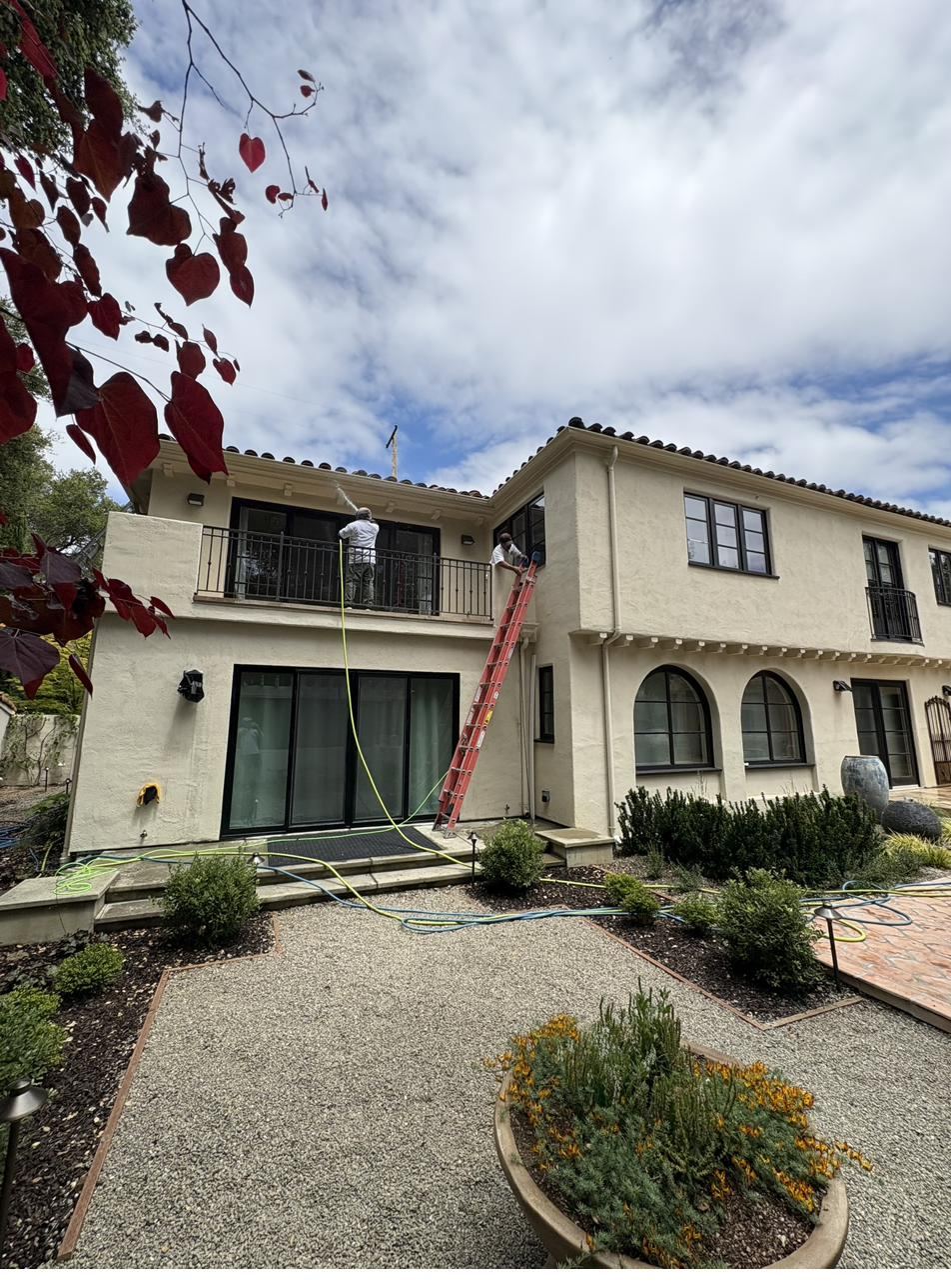 Two Nick's Pressure Washing technicians washing the exterior of a Spanish-style estate
